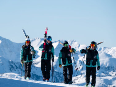 ROC Skilehrer stehen mit den Skiern auf den Schultern vor den Dolomiten